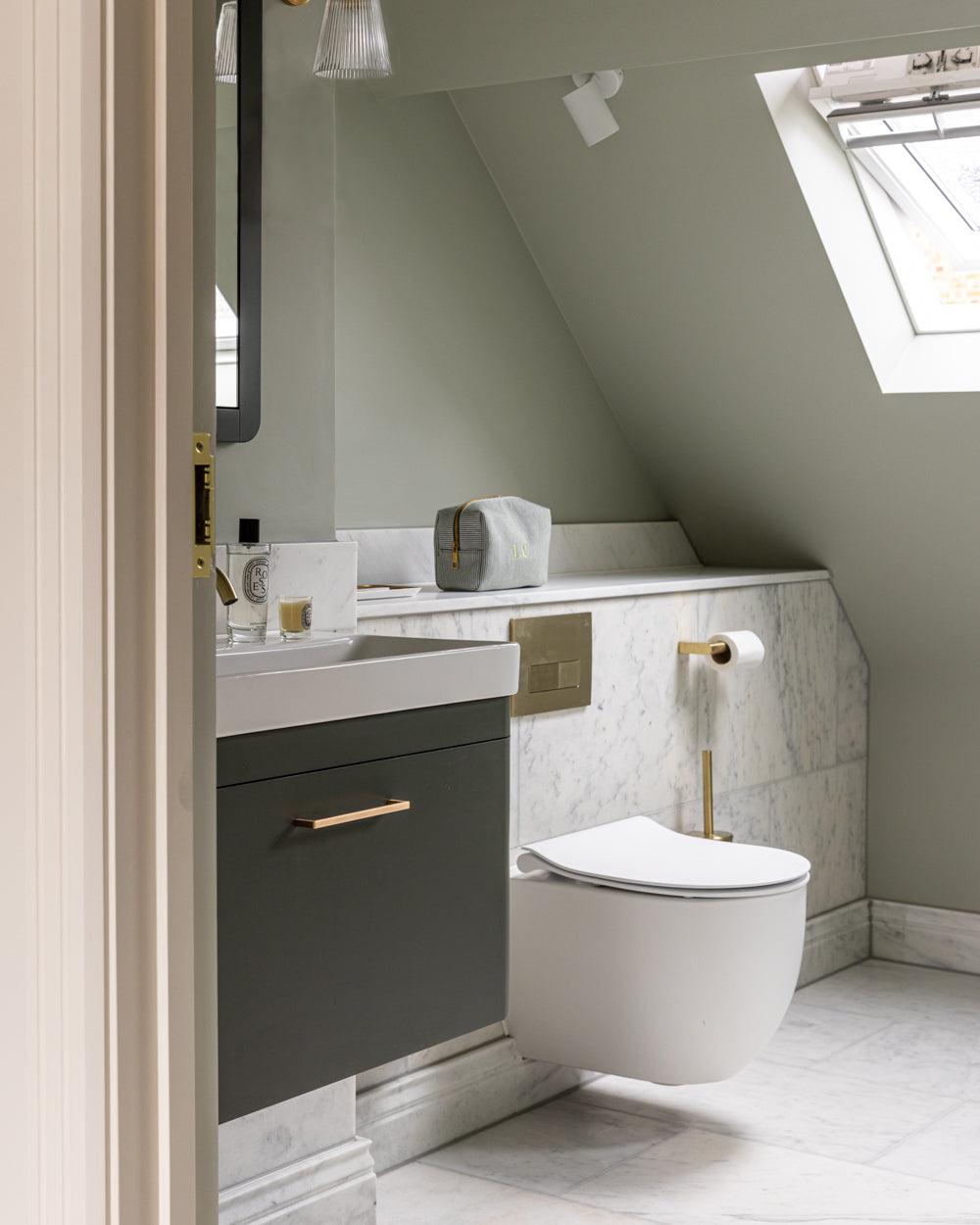 Long Island Marble Honed Finish on the floor and half-height walls of a sage green loft cloakroom with brass fittings