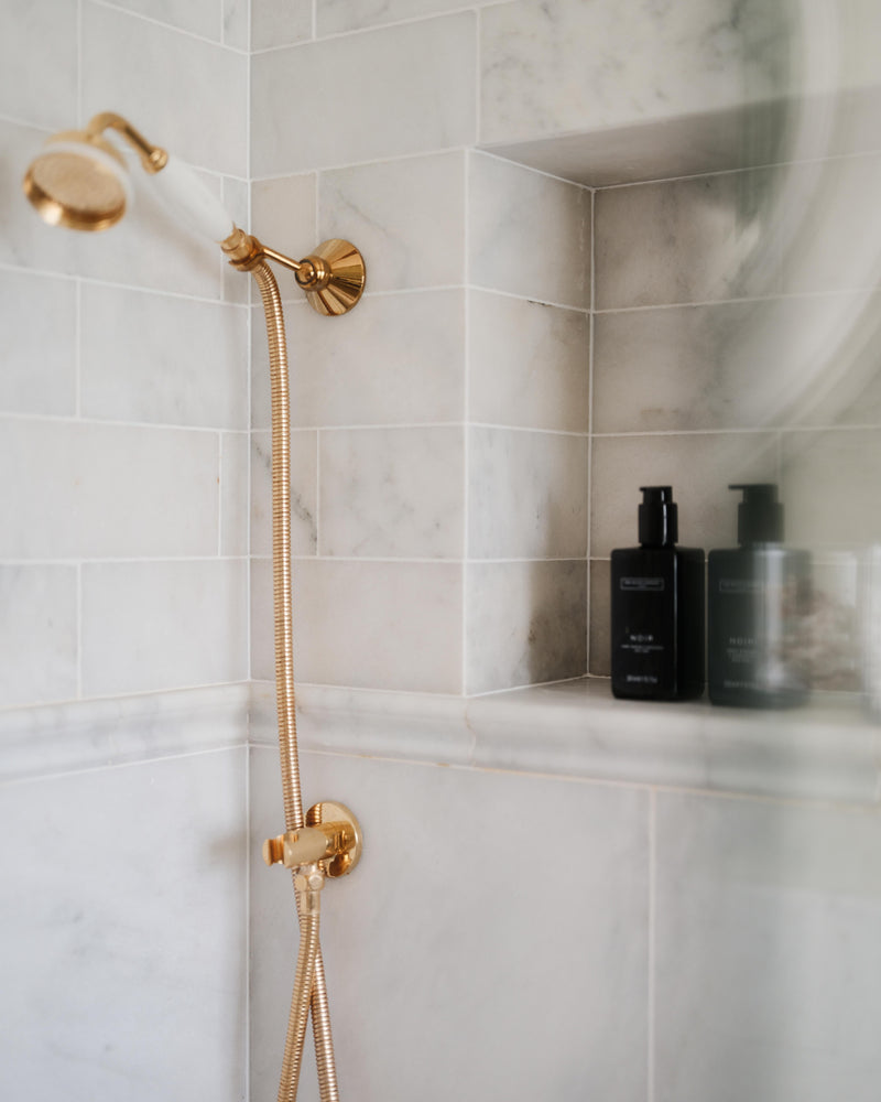 Long Island Marble Honed Finish tiled shower wall with a recessed niche, moulded border course and polished brass shower