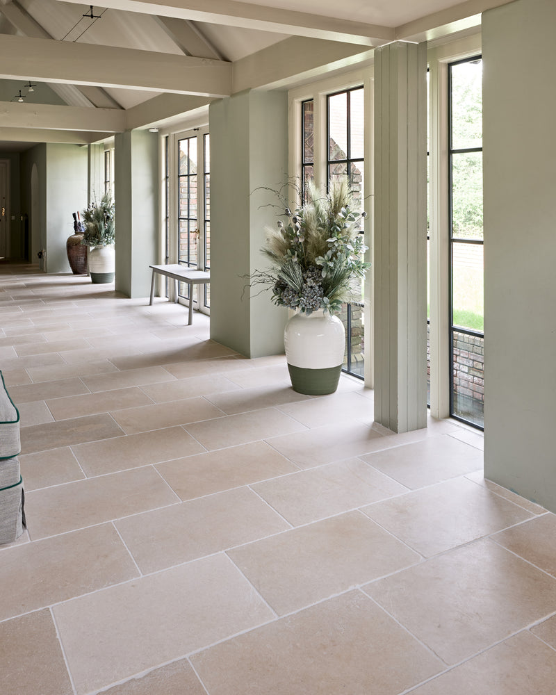 Mallory Limestone Tumbled Finish laid through a sage green garden room corridor with steel casement doors and tall planted urns