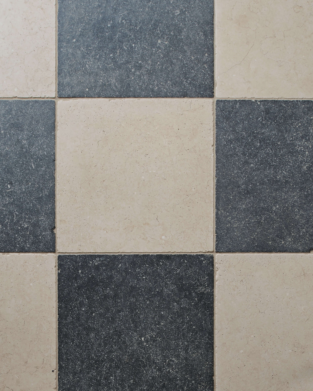 Close-up of Mallory Limestone Tumbled Finish laid in a chequerboard with dark limestone, showing the tumbled edges and surface texture