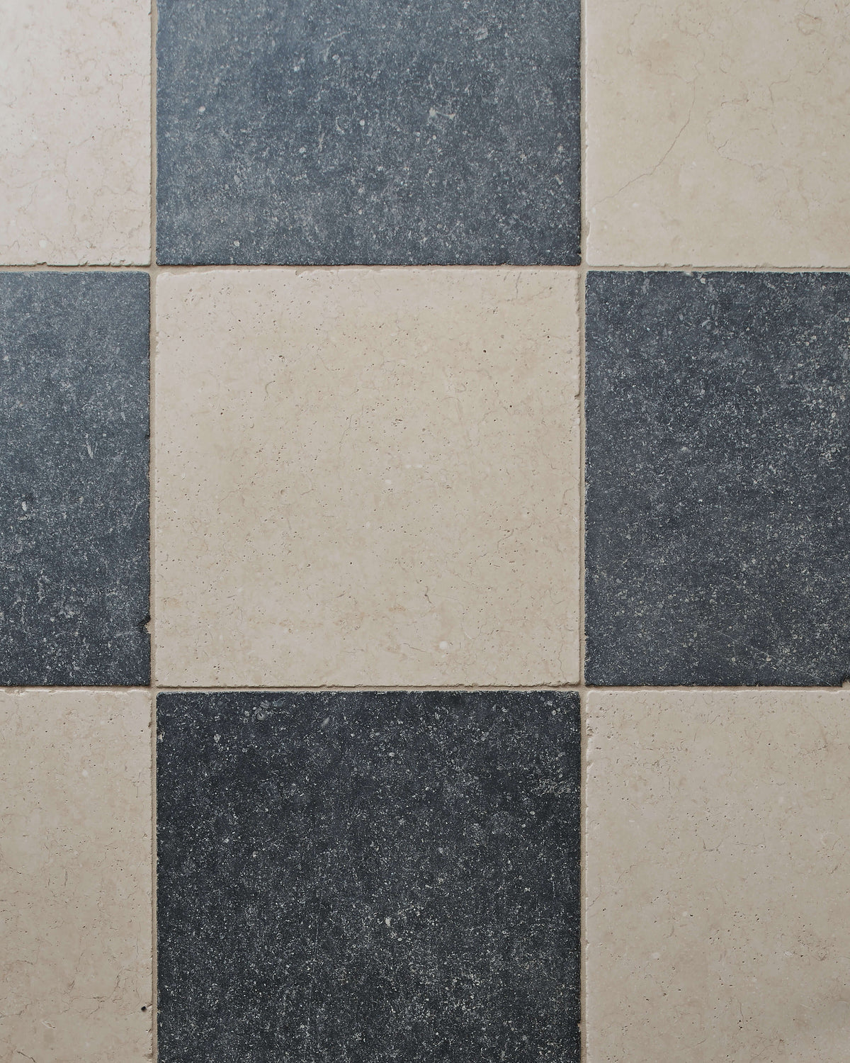 Close-up of Mallory Limestone Tumbled Finish laid in a chequerboard with dark limestone, showing the tumbled edges and surface texture