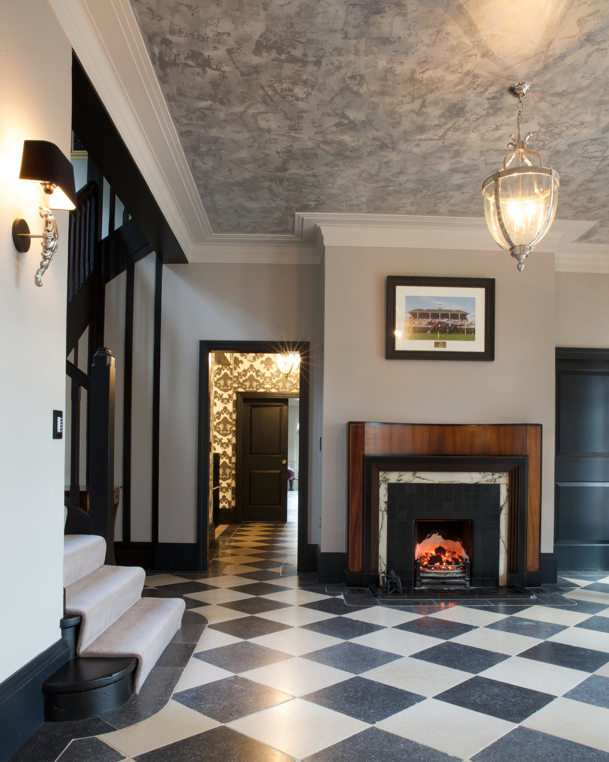 Mallory Limestone Tumbled Finish in a chequerboard with dark limestone across an entrance hall with a fireplace and staircase