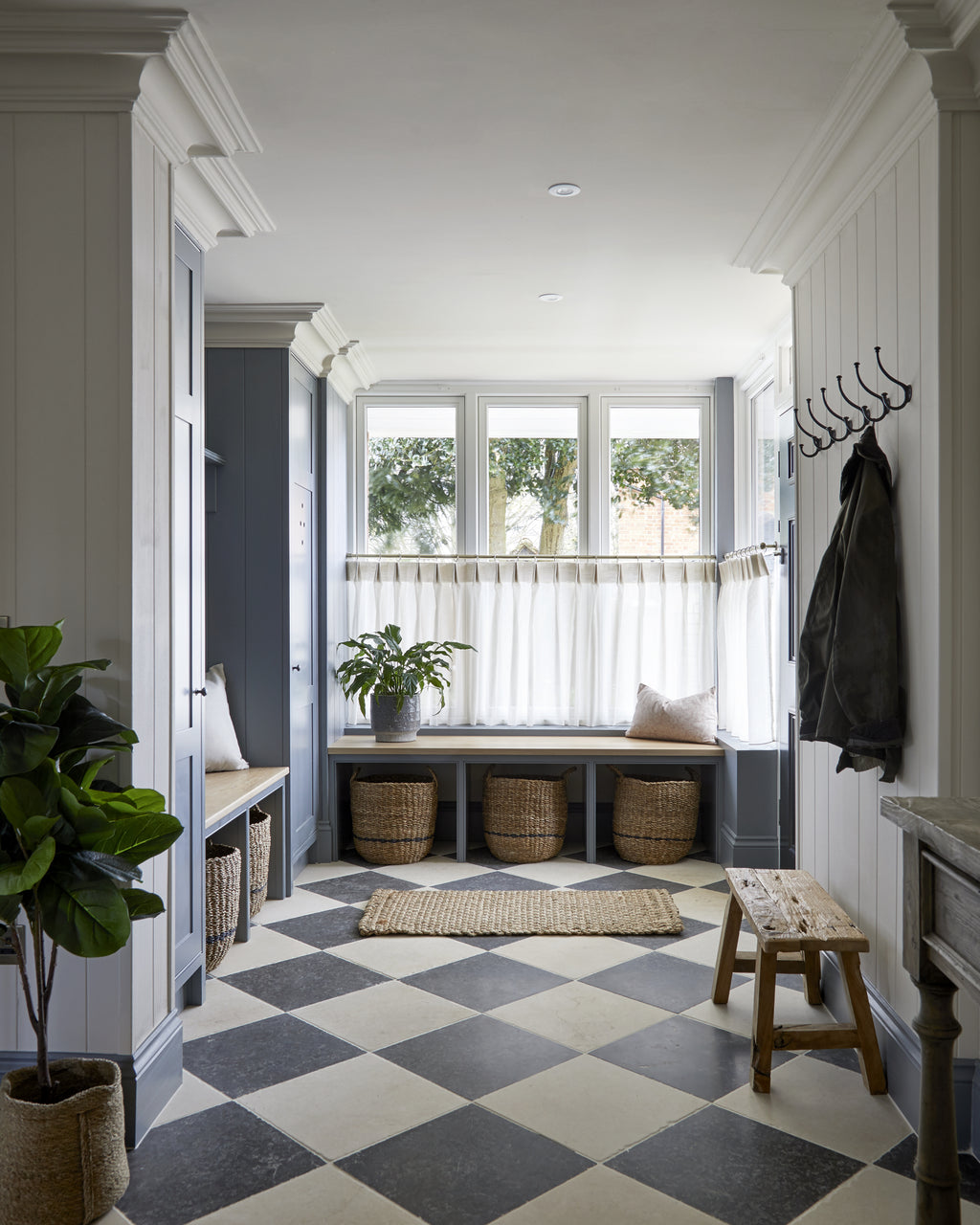 Mallory Limestone Tumbled Finish in a chequerboard with dark limestone through a panelled mud room with bench seating and woven baskets