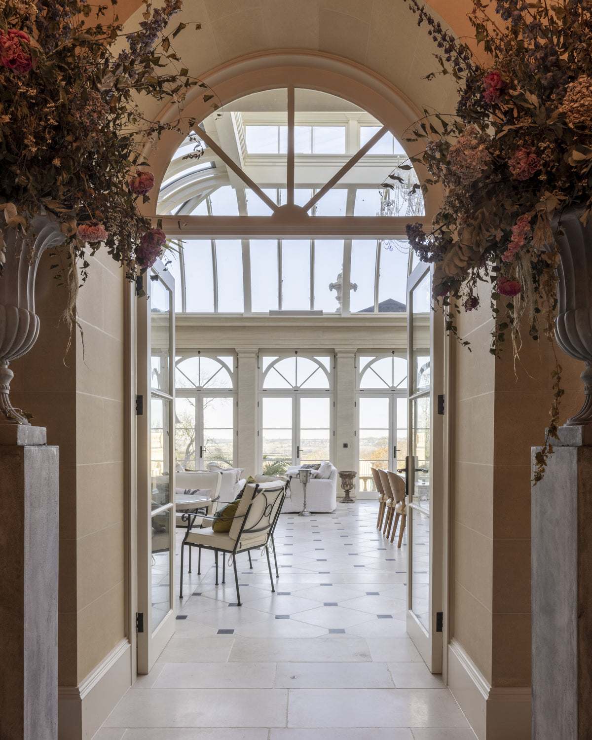 Mallory Limestone Tumbled Finish laid through a stone archway looking into an orangery, with dark cabochon insets beyond