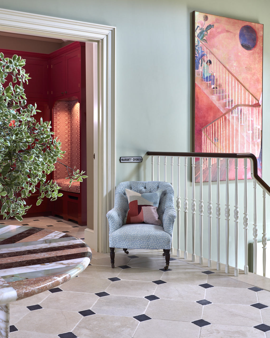 Mallory Limestone Tumbled Finish in an octagon and cabochon pattern on a landing beside a red lacquered cloakroom