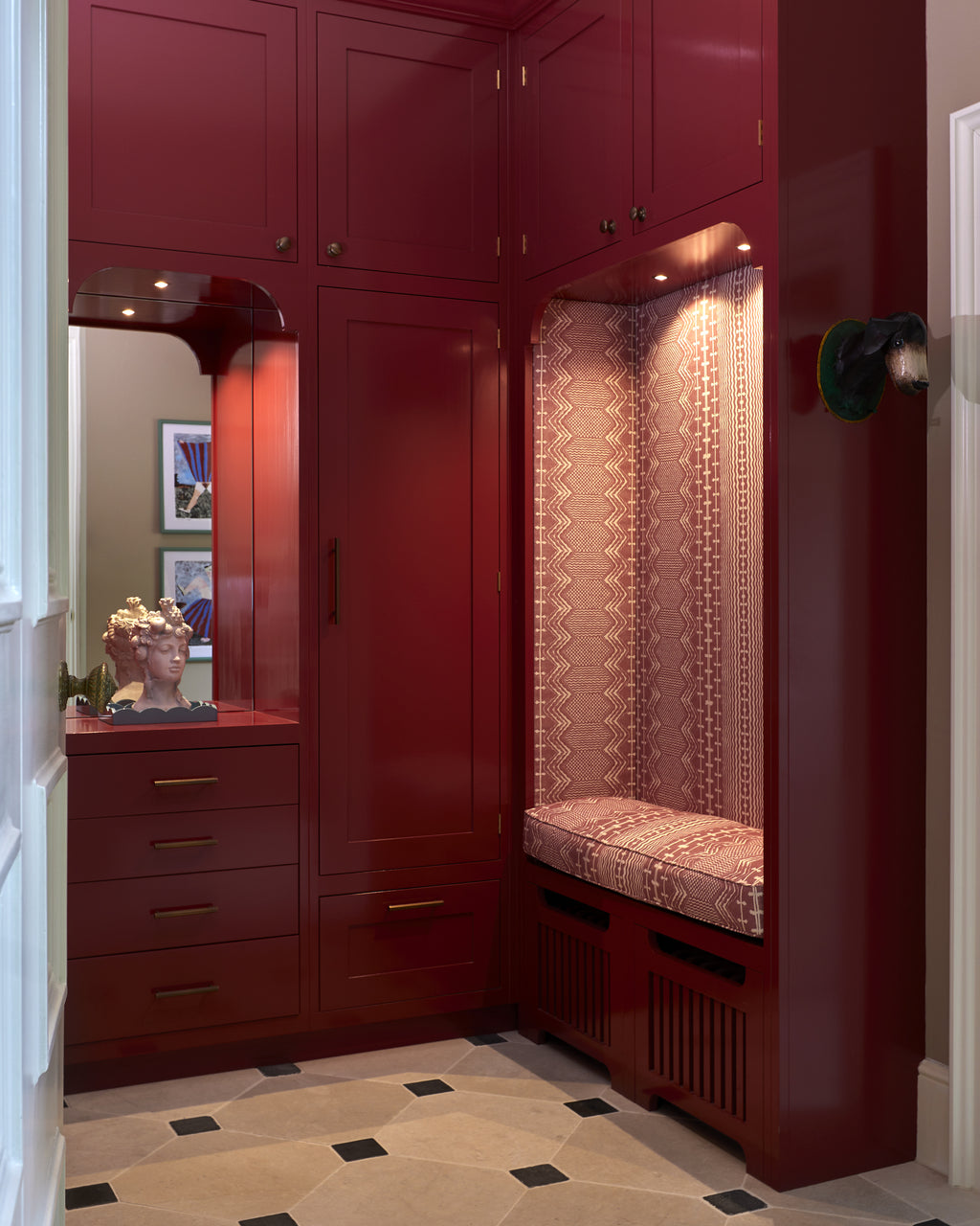 Mallory Limestone Tumbled Finish in an octagon and cabochon pattern across the floor of a red lacquered cloakroom with a fitted bench