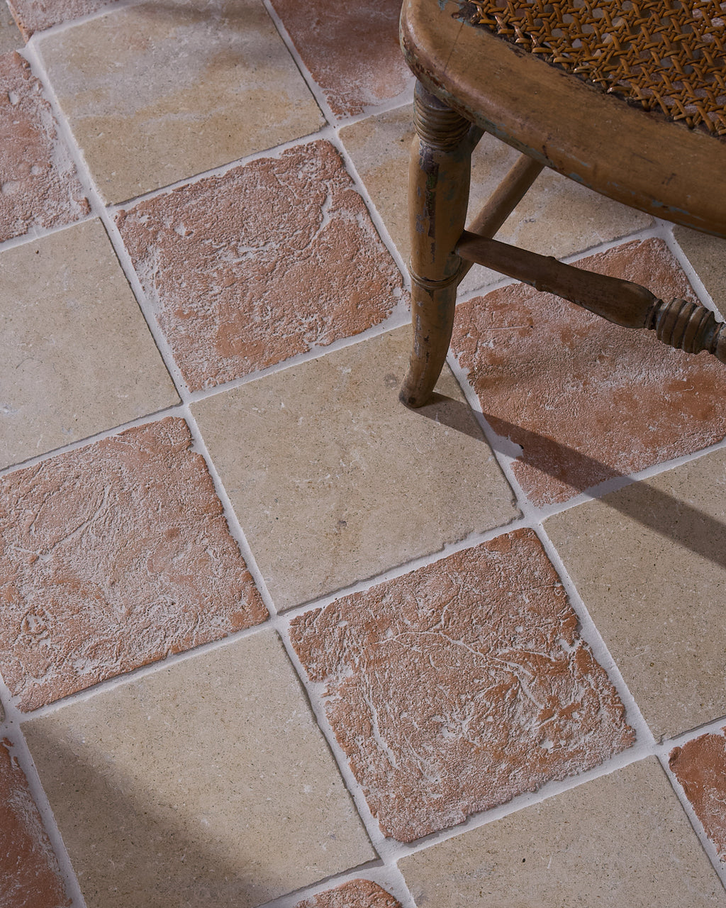 Marlborough Terracotta Square laid in a checkerboard with Buscot Limestone Tumbled 20 x 20, beneath the turned leg of an antique cane-seated chair