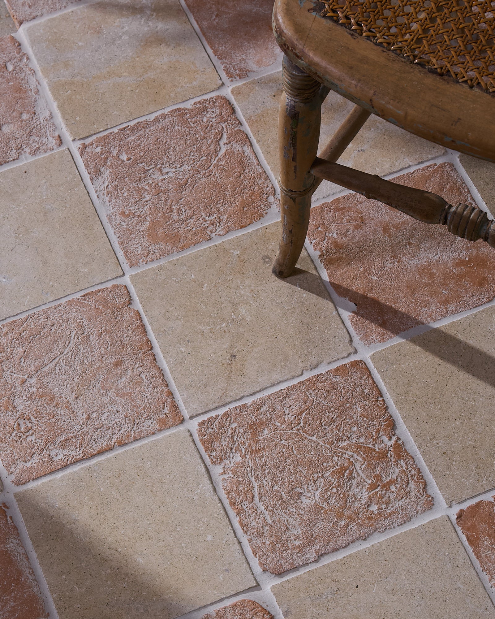 Marlborough Terracotta Square laid in a checkerboard with Buscot Limestone Tumbled 20 x 20, beneath the turned leg of an antique cane-seated chair