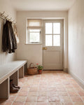 Marlborough Terracotta Square across a boot room floor, with a limewashed panelled bench, brass coat hooks and a stable door to the garden