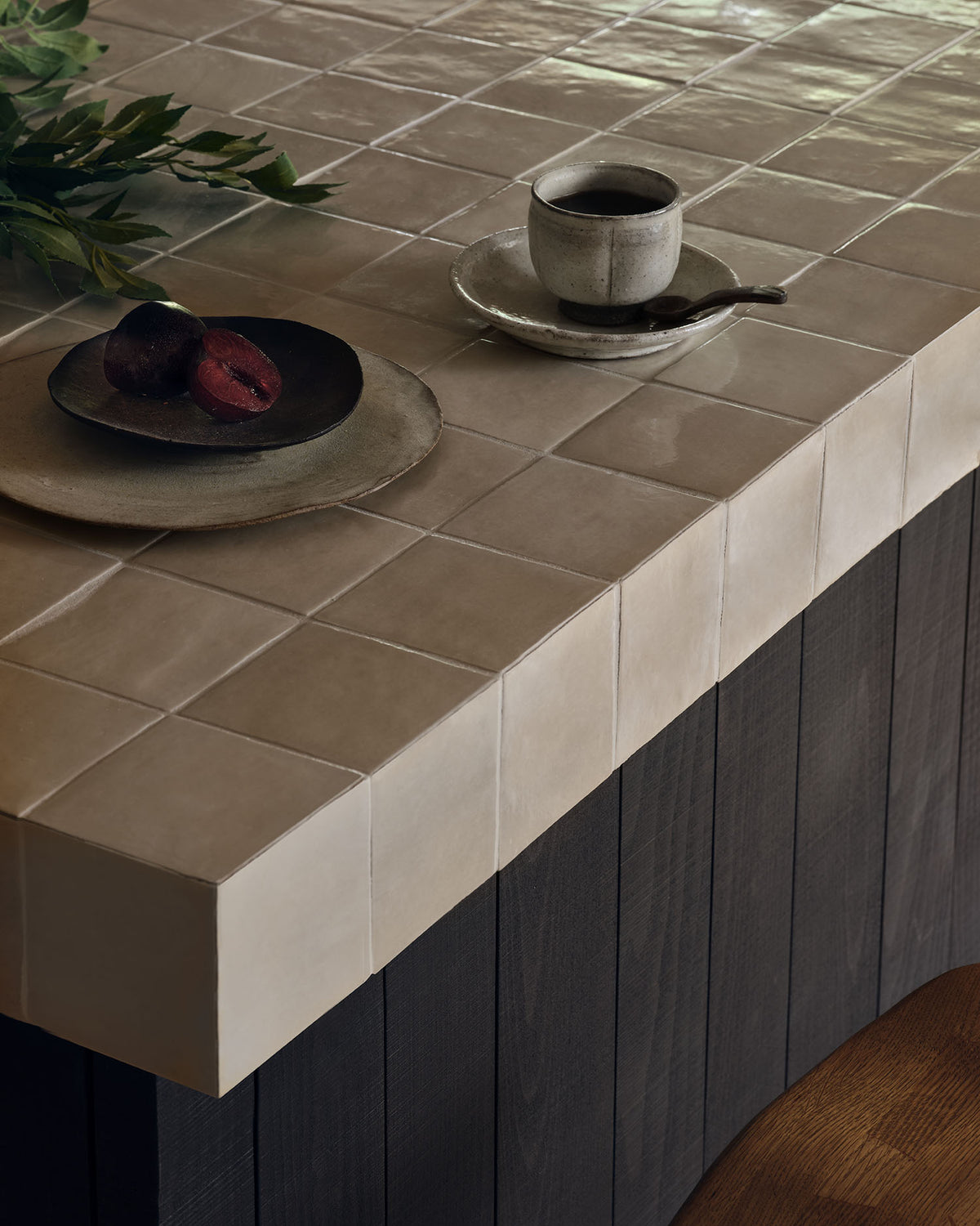 Close-up of the corner of a Maroc Ceramic Beige tiled worktop, showing the glossy undulating glaze wrapping over the edge onto a dark timber island