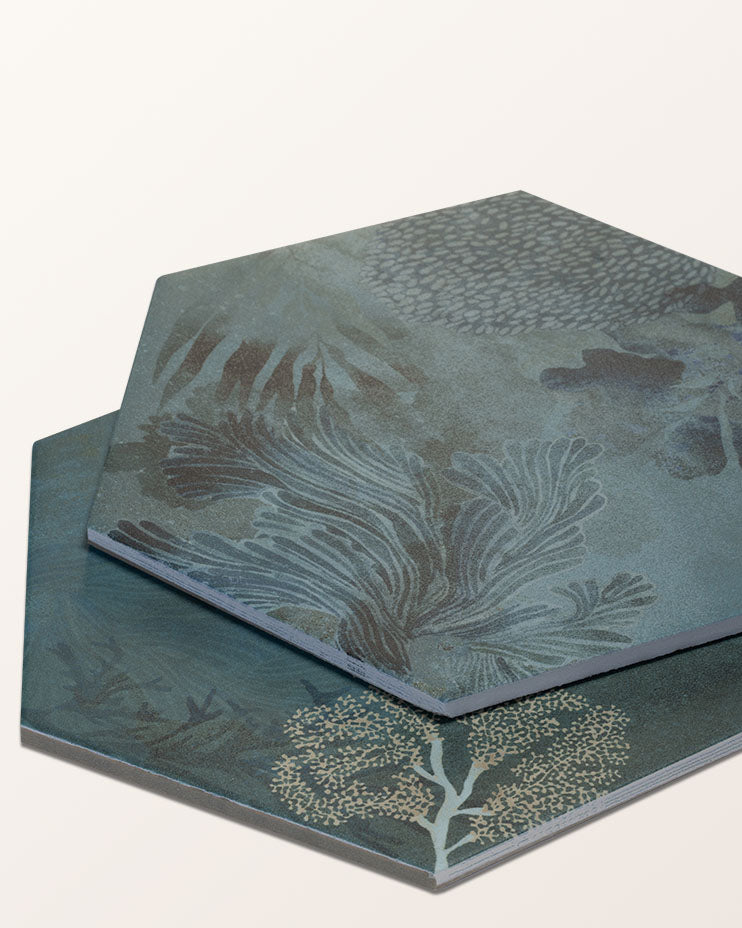 Two Mermaid's Garden Porcelain hexagon tiles stacked at an angle on a plain cream background, showing the teal glaze and gold coral detail