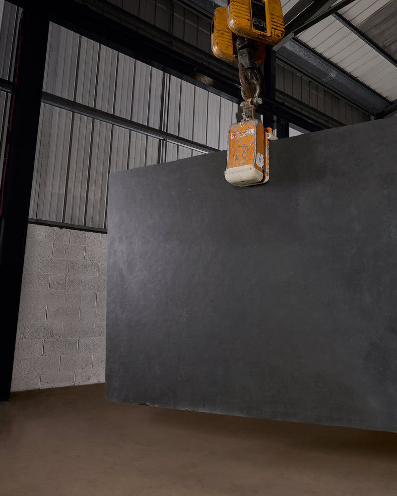 A full Metropolitan Slate Riven Slab lifted by a vacuum crane grab in the warehouse, showing the scale of a single uncut sheet