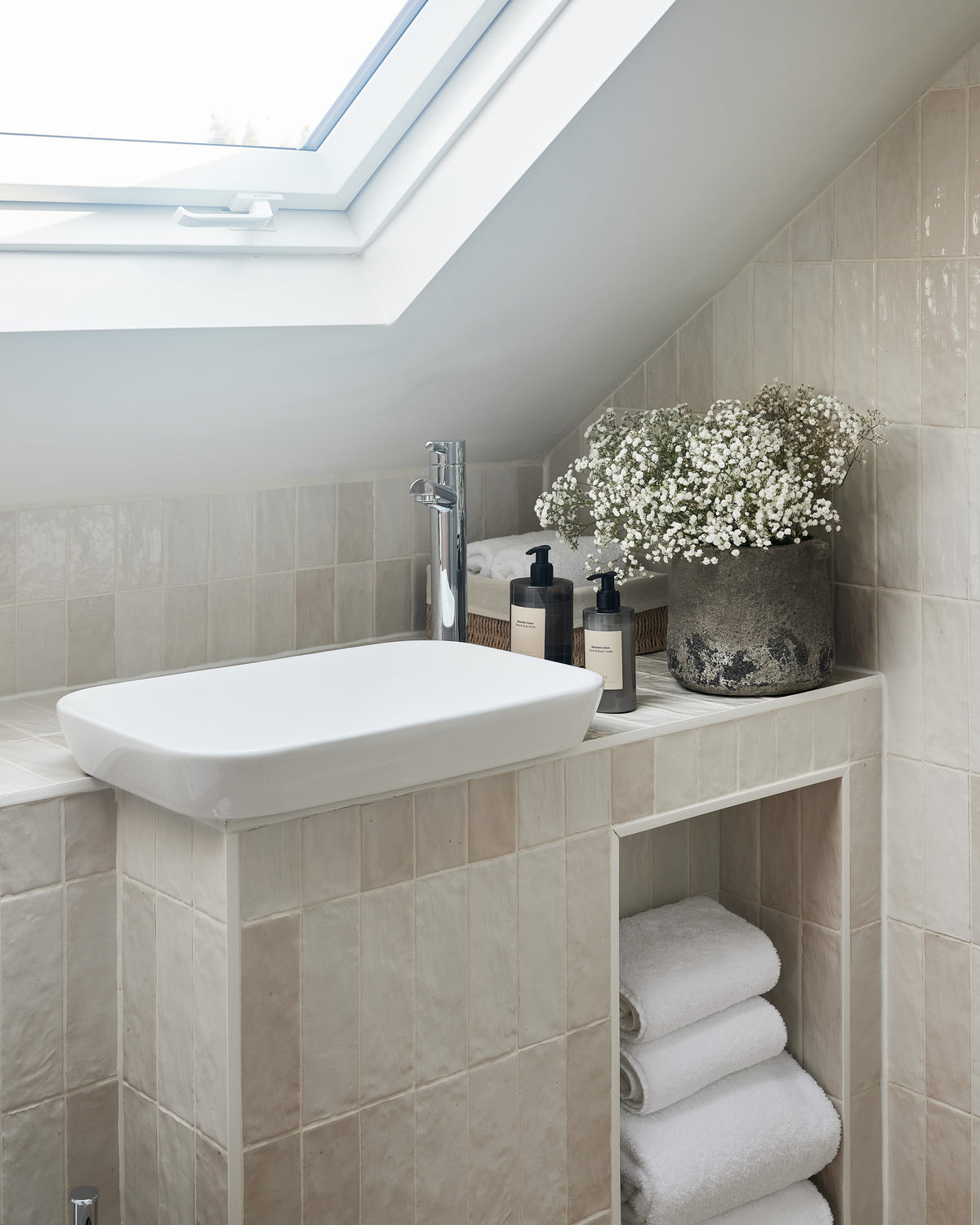 Oasis Ceramic White Gloss tiling the vanity and sloping wall of a loft bathroom beneath a skylight, with towels stacked in an open alcove