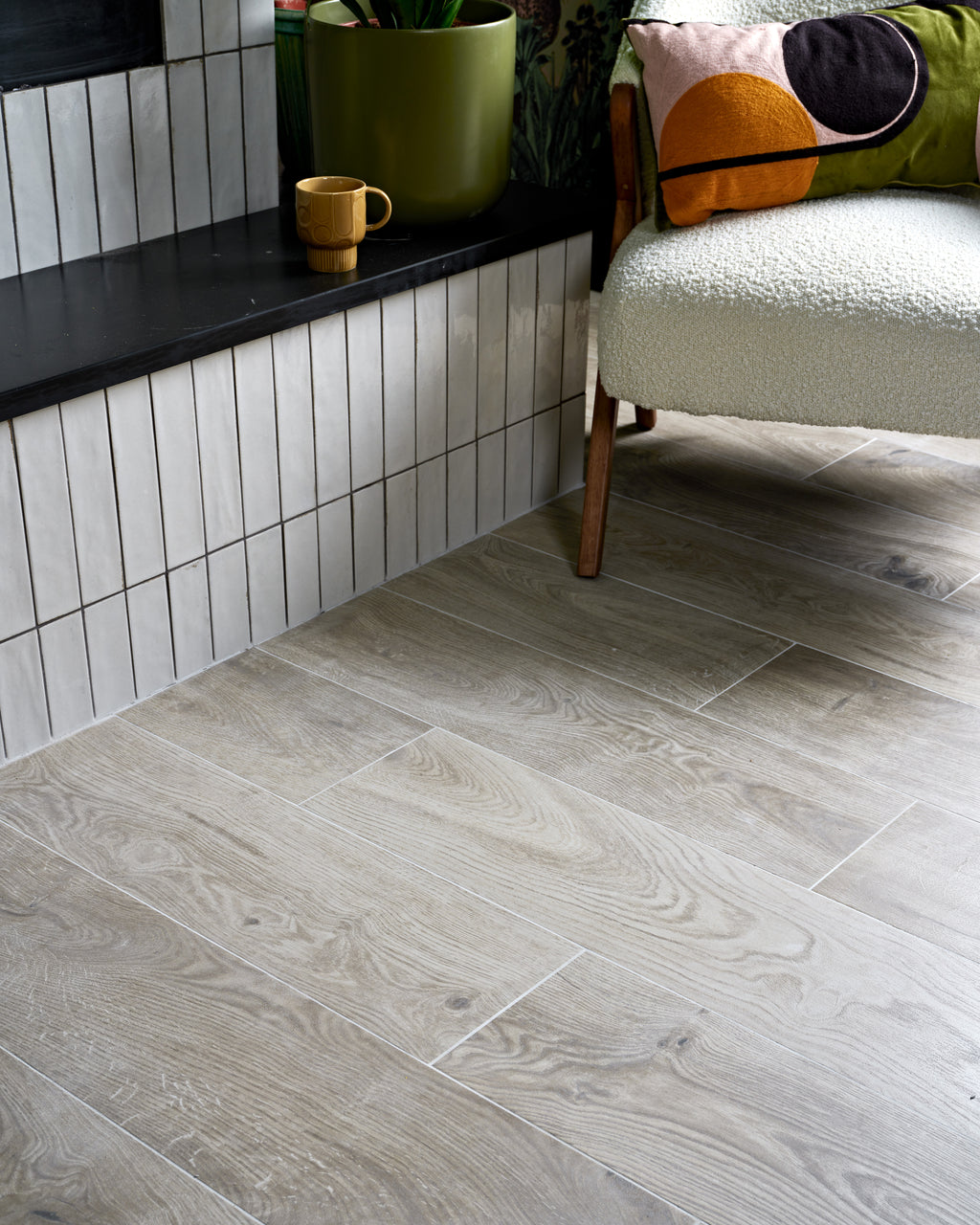 Parterre Porcelain Plank laid in a staggered plank pattern up to a hearth bench tiled in Foundry Leadenhall White, with a boucle armchair alongside