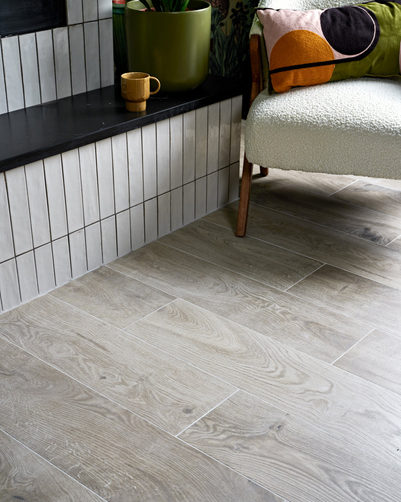 Parterre Porcelain Plank laid in a staggered plank pattern up to a hearth bench tiled in Foundry Leadenhall White, with a boucle armchair alongside