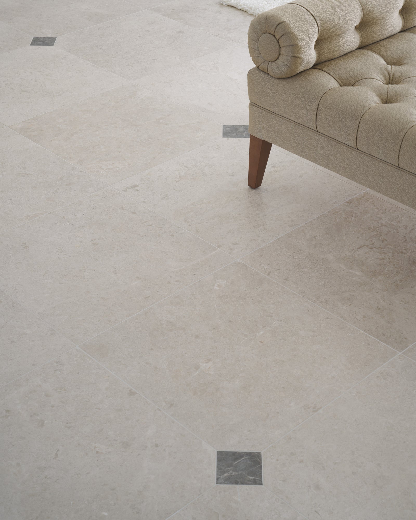 Close view of Piccadilly Limestone Honed Finish showing the fossil detail in the stone and the grey cabochon insets at the tile junctions