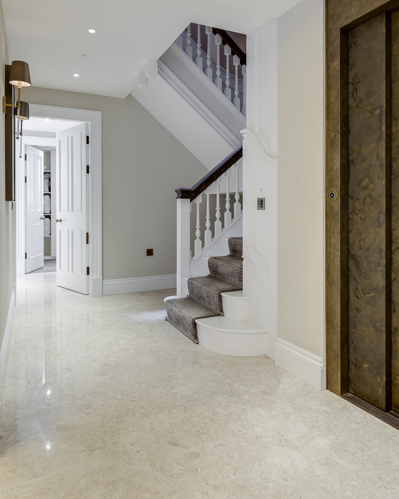 Piccadilly Limestone Honed Finish running through a pale landing with a bronze panelled door and carpeted stair