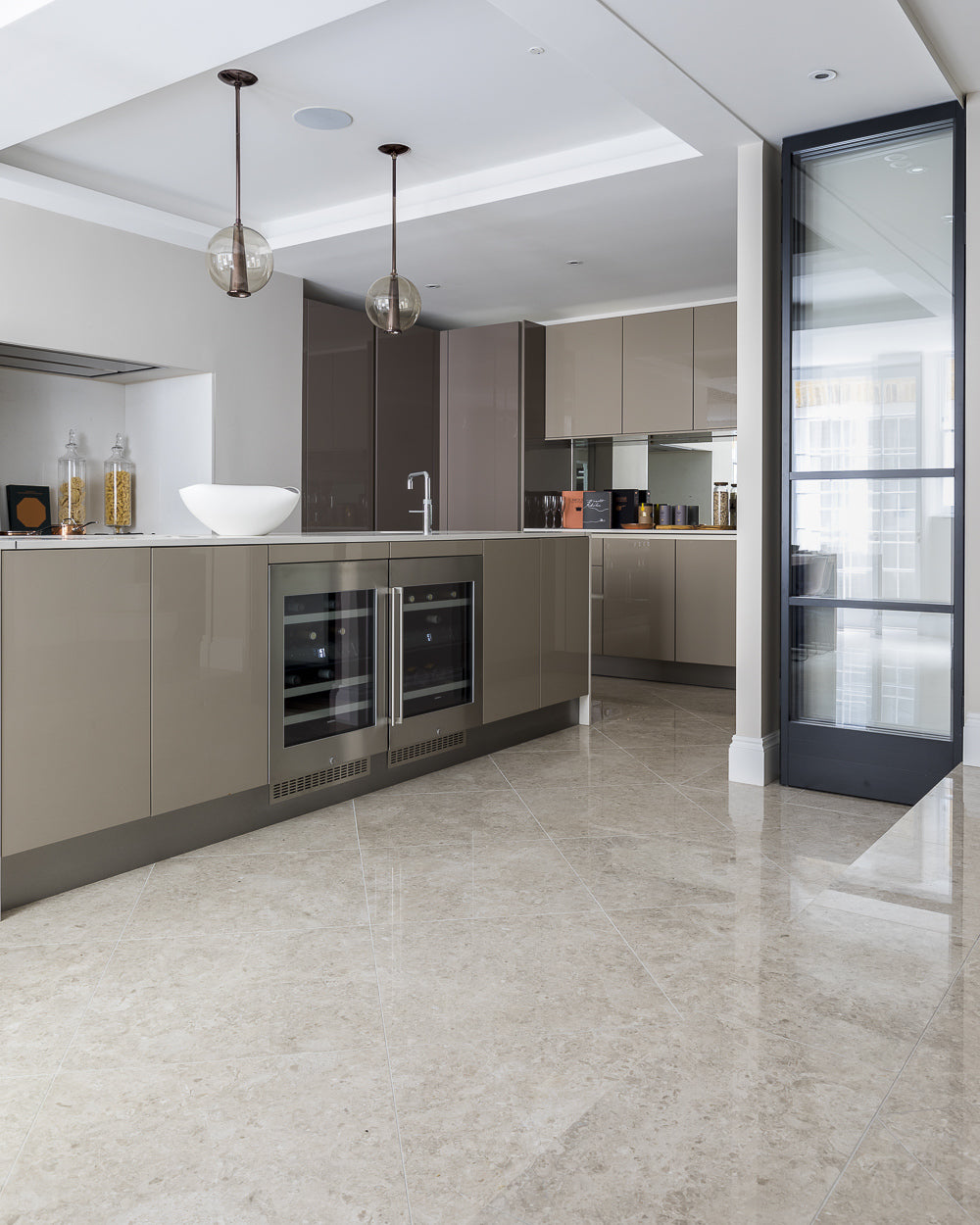 Piccadilly Limestone Honed Finish laid on the diagonal in a contemporary kitchen with taupe gloss cabinetry and glass pendants