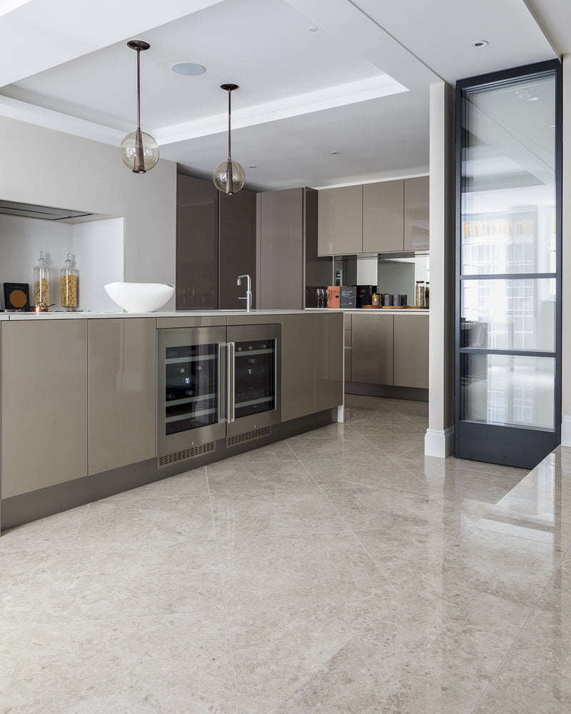 Piccadilly Limestone Honed Finish laid on the diagonal in a contemporary kitchen with taupe gloss cabinetry and glass pendants