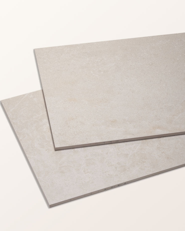 Two Riverside Porcelain Perla tiles overlapping at an angle against a pale background, showing the surface variation and the tile edge profile