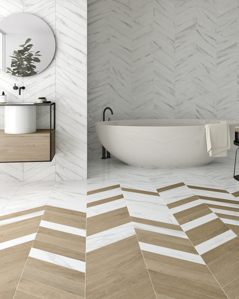 Rotterdam Porcelain Calacatta laid in a chevron across the walls and floor of a bathroom, mixed with wood effect chevron tiles around a freestanding bath