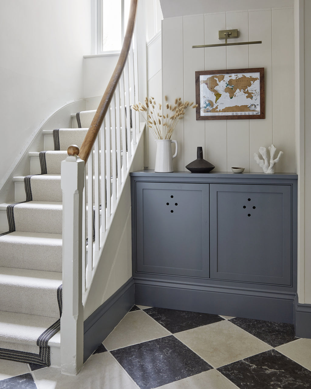 Royal Mink Limestone Tumbled Finish in a chequerboard with Mallory Limestone at the foot of a carpeted staircase, beside a grey radiator cabinet