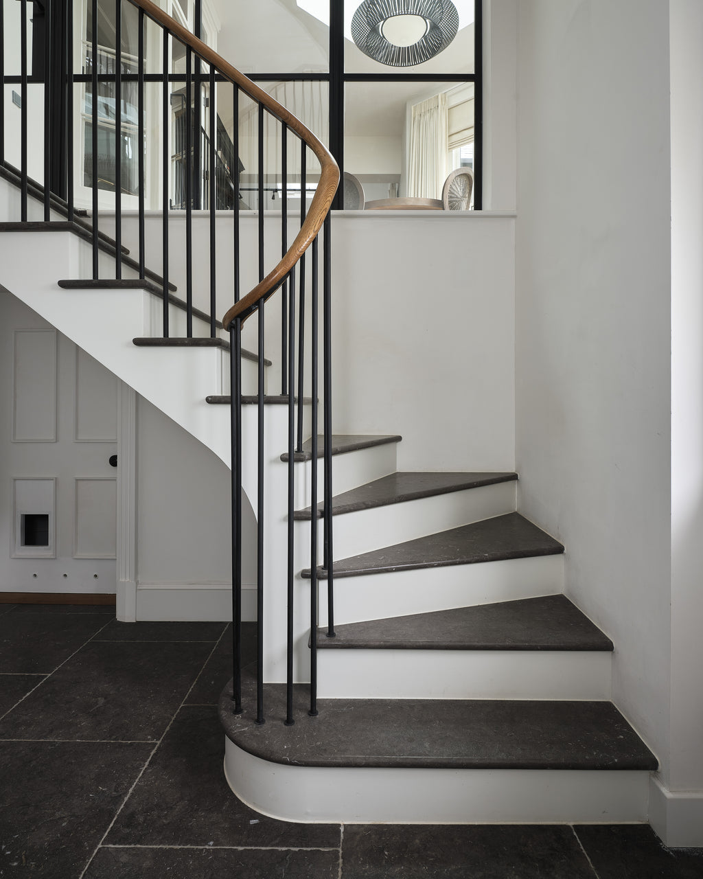 Royal Mink Limestone Tumbled Finish used for both the floor and the winder treads of a curved staircase with a slim black balustrade