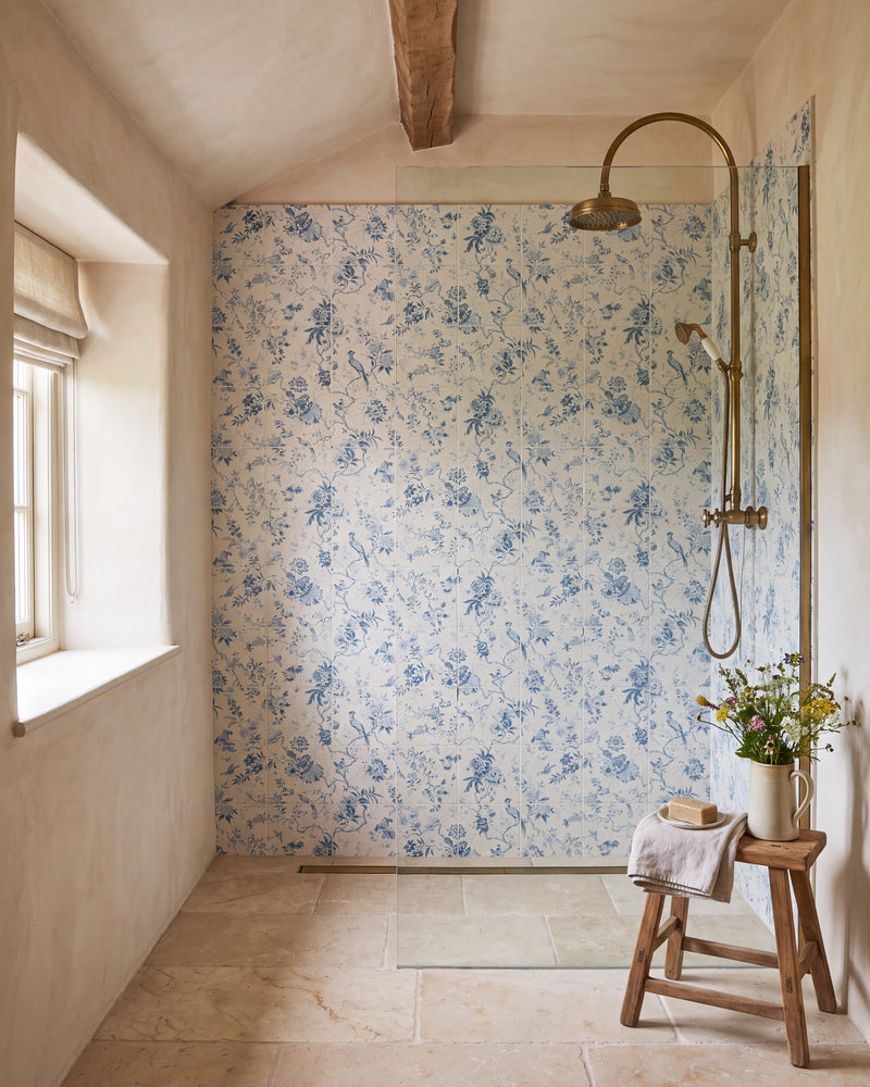 Sanderson Pillemont Toile China Blue Mural Porcelain lining a walk-in shower in a beamed cottage bathroom, with an aged brass rainfall shower and a limestone floor