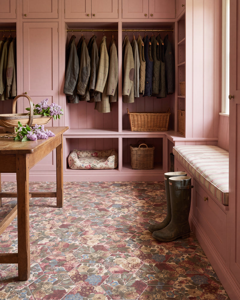 Sanderson Very Rose & Peony Madder Porcelain hexagons underfoot in a pink-painted boot room, with hanging tweed and waxed jackets, wicker baskets, a striped window seat and a floral dog bed
