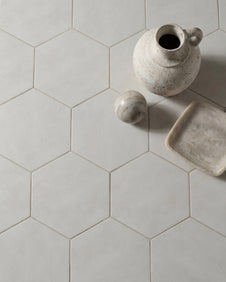 Shadow White Hex Field Porcelain in a close overhead view with a speckled stoneware jug, marble sphere and alabaster dish