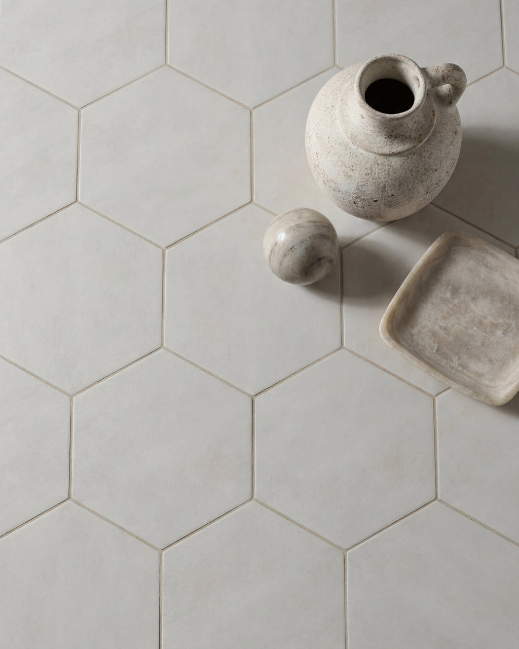 Shadow White Hex Field Porcelain in a close overhead view with a speckled stoneware jug, marble sphere and alabaster dish