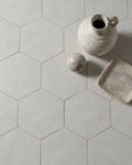 Shadow White Hex Field Porcelain in a close overhead view with a speckled stoneware jug, marble sphere and alabaster dish
