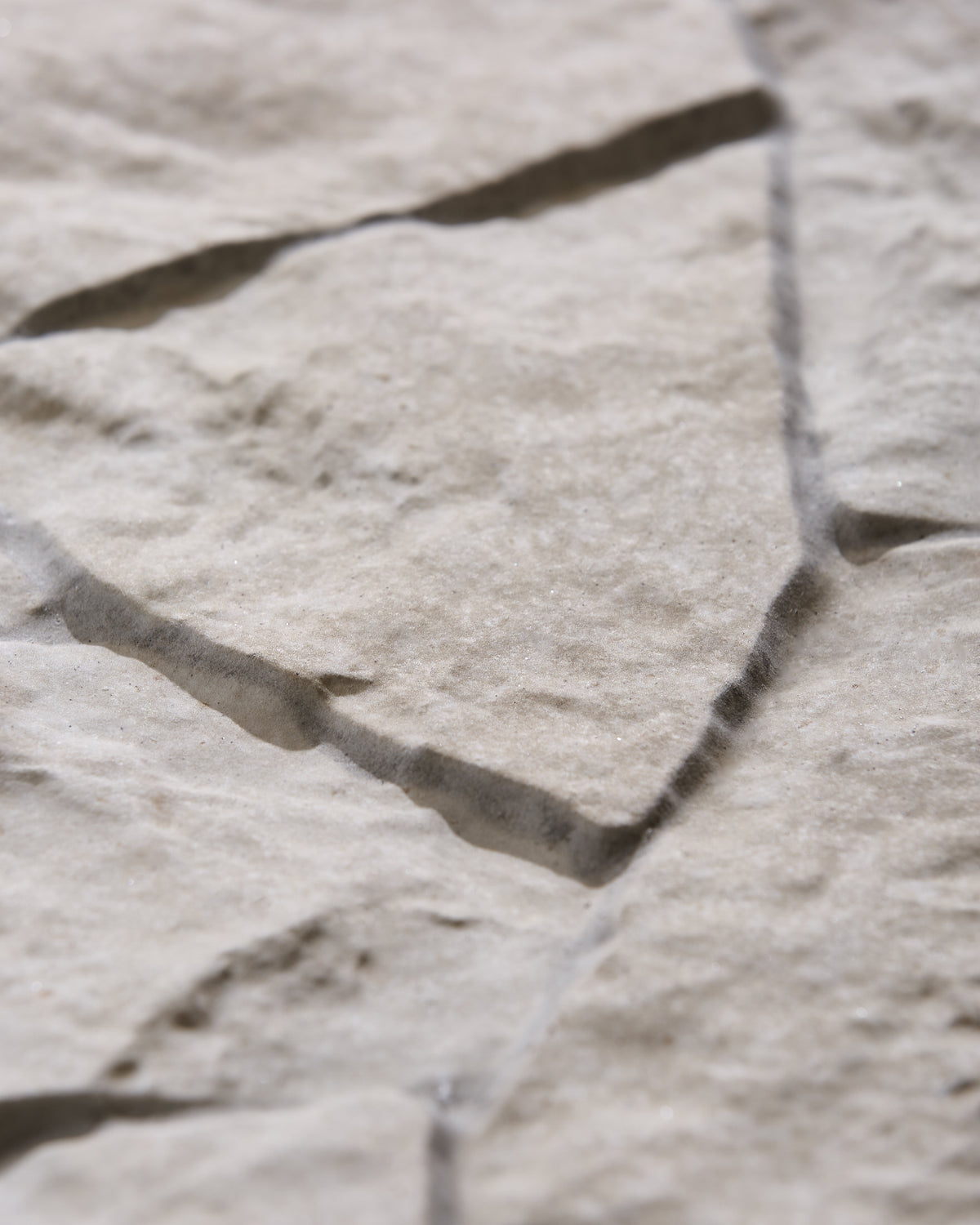 Sierra Porcelain Textured in raking light, close up on the riven edges where the pieces meet, showing the depth of the split-stone finish