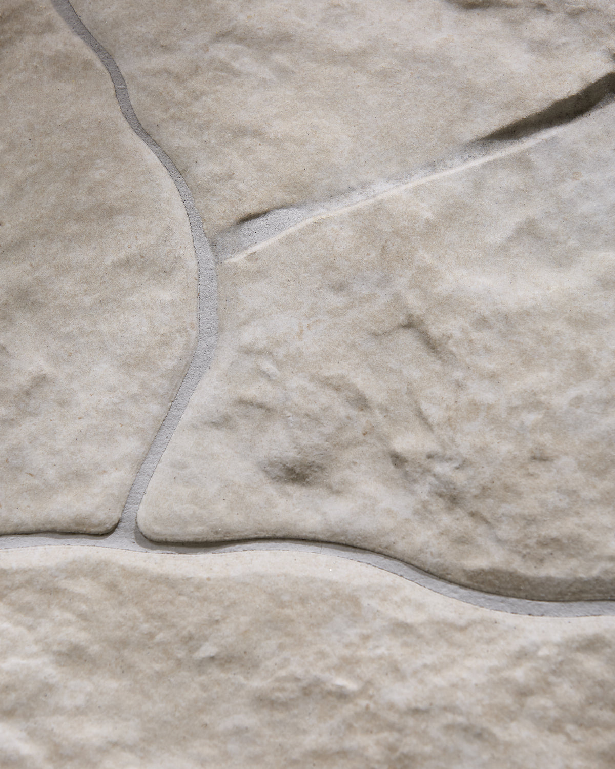 Sierra Porcelain Textured close up on a curved grout line between two large pieces, with the soft cream surface and fine sandy speckle visible