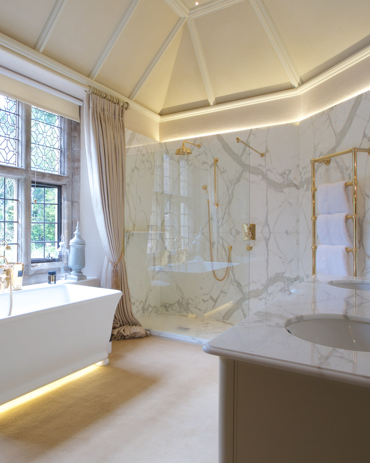 Statuario Marble Slab lining a walk-in shower and forming the vanity top in a bathroom with a coffered octagonal ceiling, leaded windows and a freestanding bath
