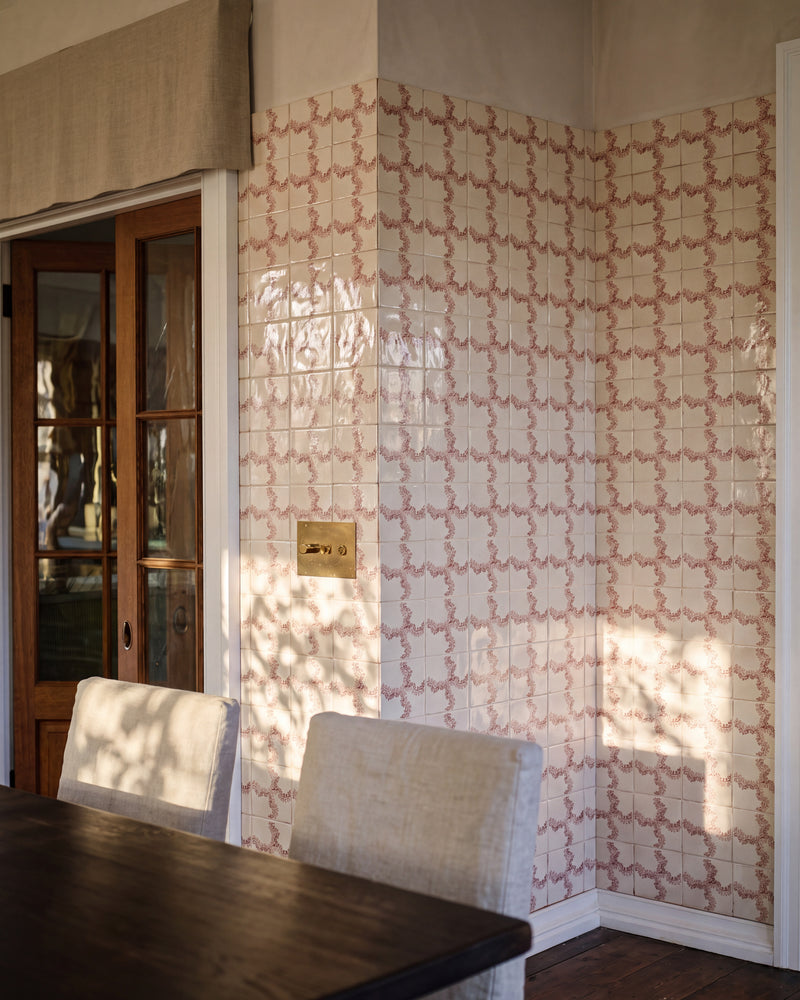 STUDIO Sanderson Oxbow Check Madder tiles wrapping a dining room corner in late afternoon light, with a dark timber table, linen slipcovered chairs, a glazed timber door and a brass switch plate