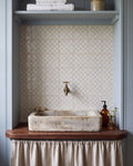 STUDIO Sanderson Rye Pottery Blue tiles forming a splashback behind an antique stone basin on a walnut washstand in a pale blue panelled cloakroom