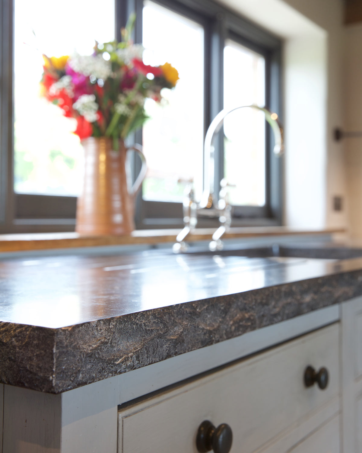 Tora Blue Honed Limestone Slab worktop edge in close focus, the rough chiselled profile set against the honed top surface