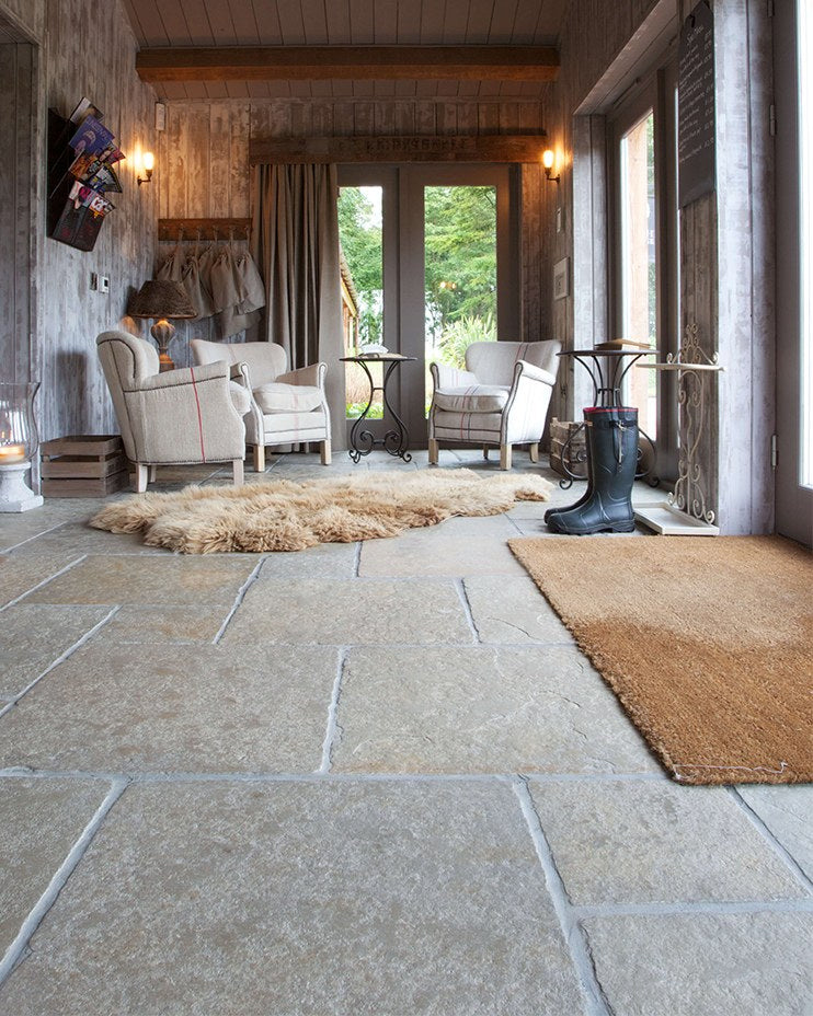 Trusloe Limestone Seasoned Finish flagstones in a country boot room with armchairs, sheepskin rug and wellington boots