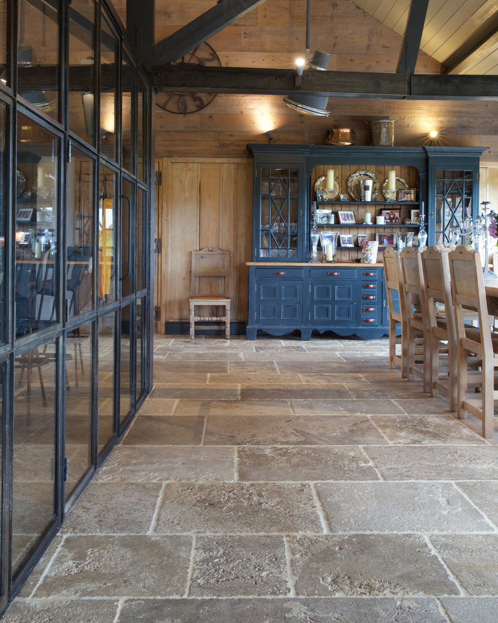Vieux Bourgogne Limestone Ancient Finish running the length of a converted barn alongside a black Crittall screen, with a blue dresser and reclaimed timber walls