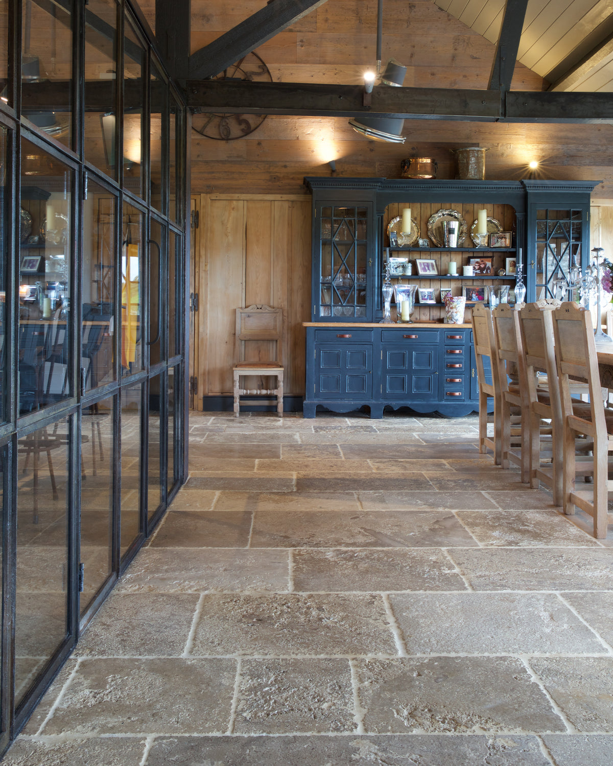 Vieux Bourgogne Limestone Ancient Finish running the length of a converted barn alongside a black Crittall screen, with a blue dresser and reclaimed timber walls